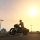 A screenshot of a man on a motorcycle watching the sun set in GTA V on PS5.